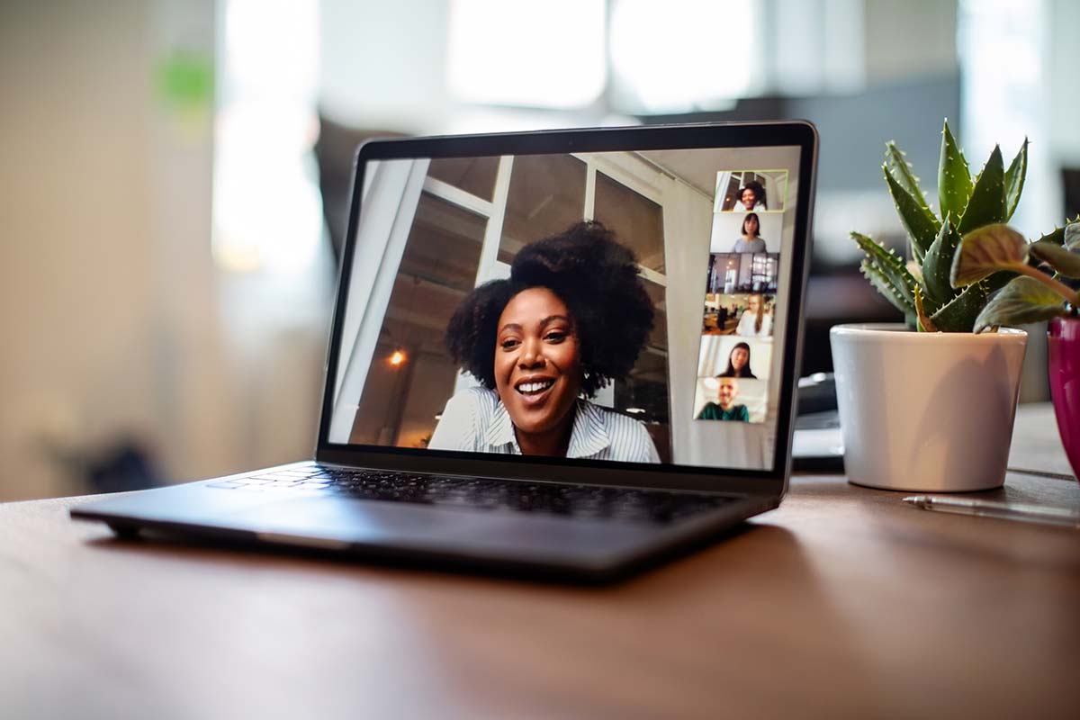 En bärbar dator på ett bord, på skärmen syns ett gruppvideosamtal med en kvinna