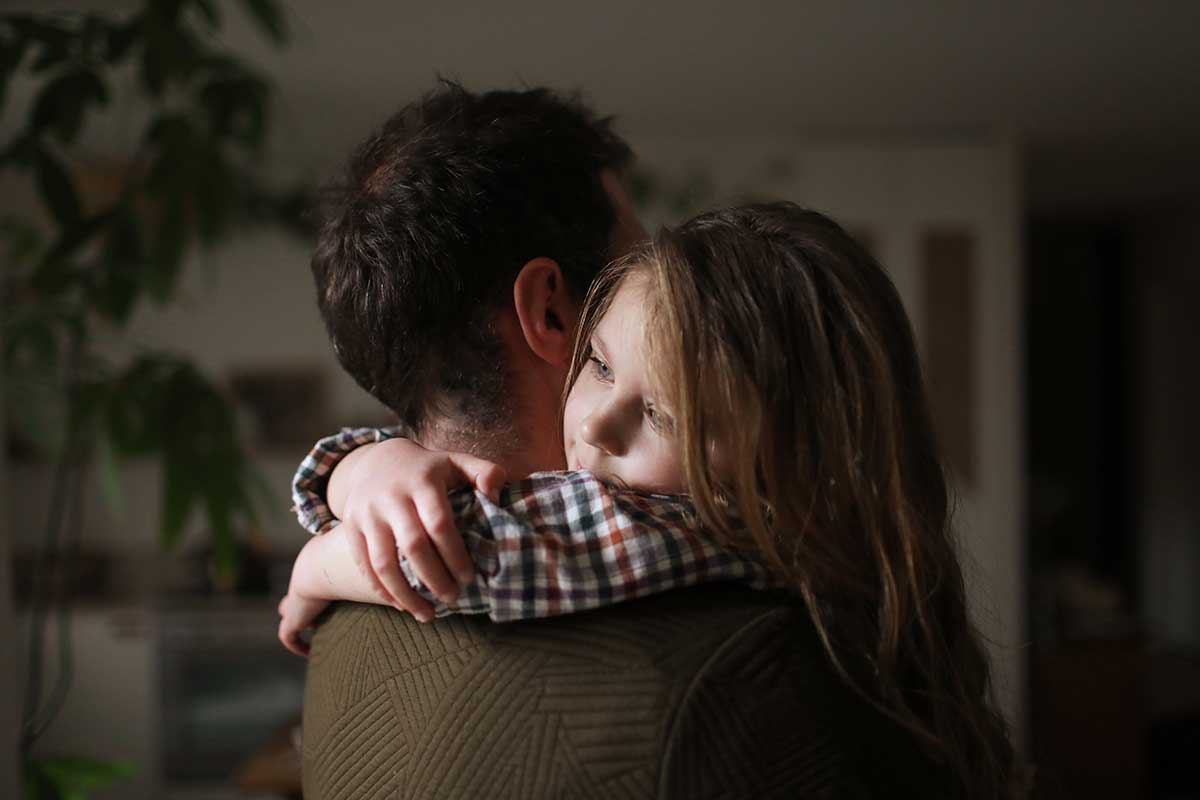 En man kramar om en ung flicka